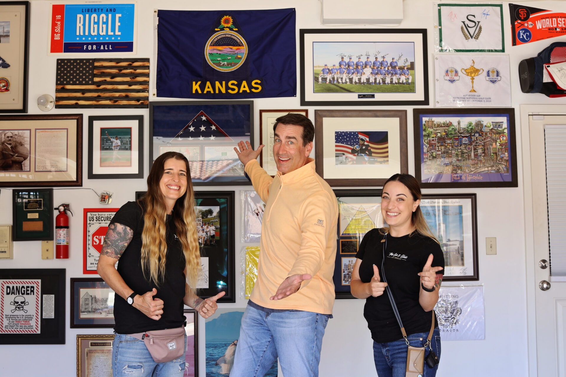 Three people standing in front of a wall with pictures on it.