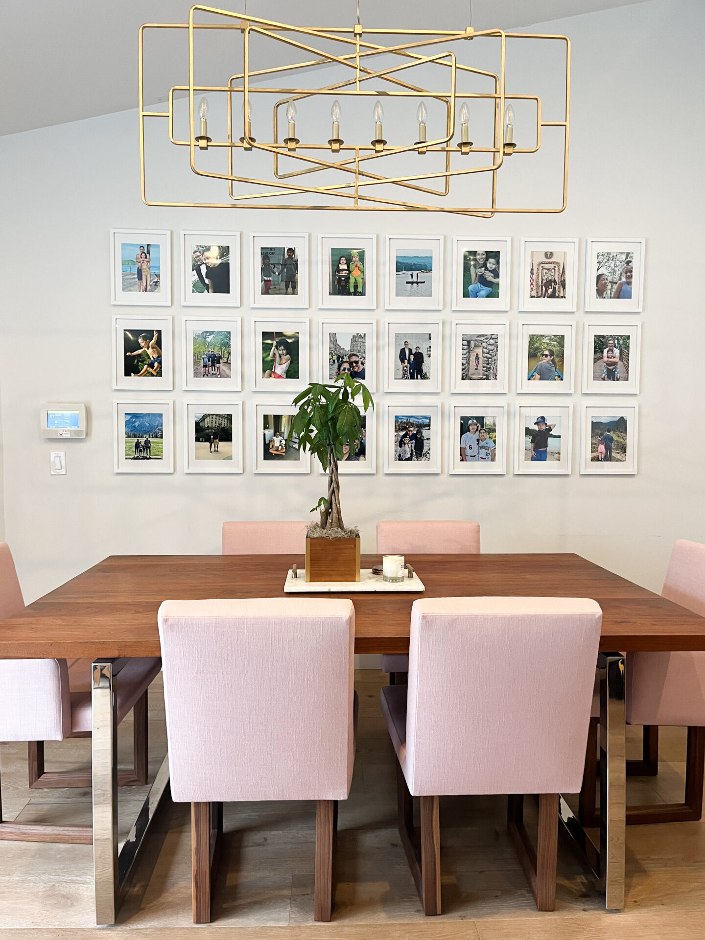 A dining room table with pink chairs and a chandelier.