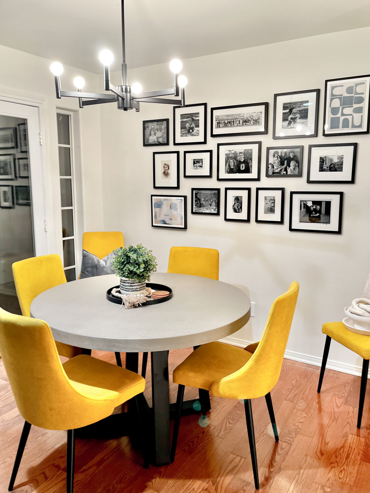 A dining room table with yellow chairs and black framed pictures on the wall.